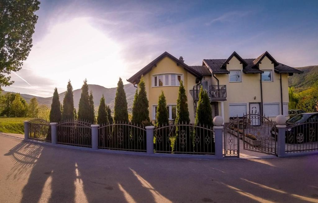a house with a gate and trees in front of it at Rooms & Apartment Jozić in Prozor