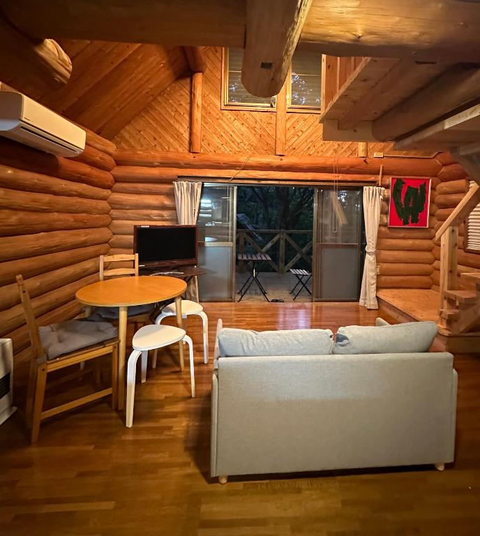 a living room with a couch and a table at Lodge Kurokawa 1 in Minamioguni