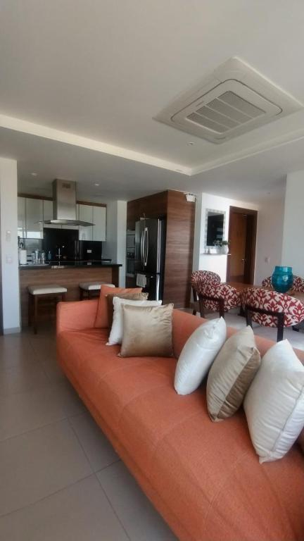 ein orangefarbenes Sofa mit weißen Kissen in einem Wohnzimmer in der Unterkunft Lujoso Dpto vista a ciudad Edificio Poseidón in Manta