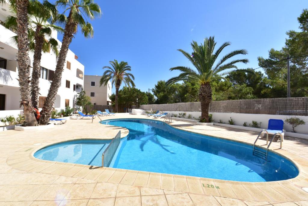 a swimming pool in a resort with palm trees at Costamar 15 - Pool - 3 minutes to the beach in Es Pujols