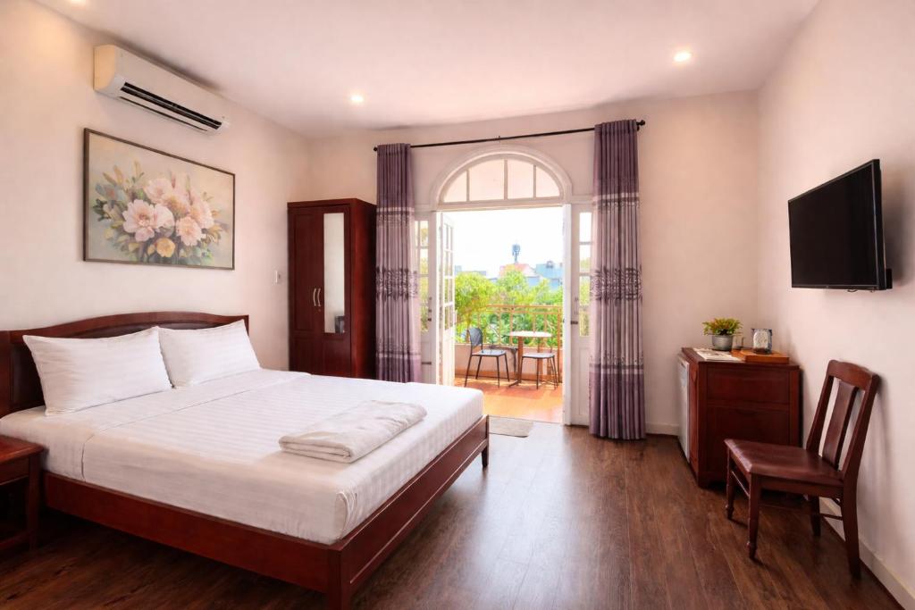 a bedroom with a bed and a tv and a window at Salyna Motel in Danang