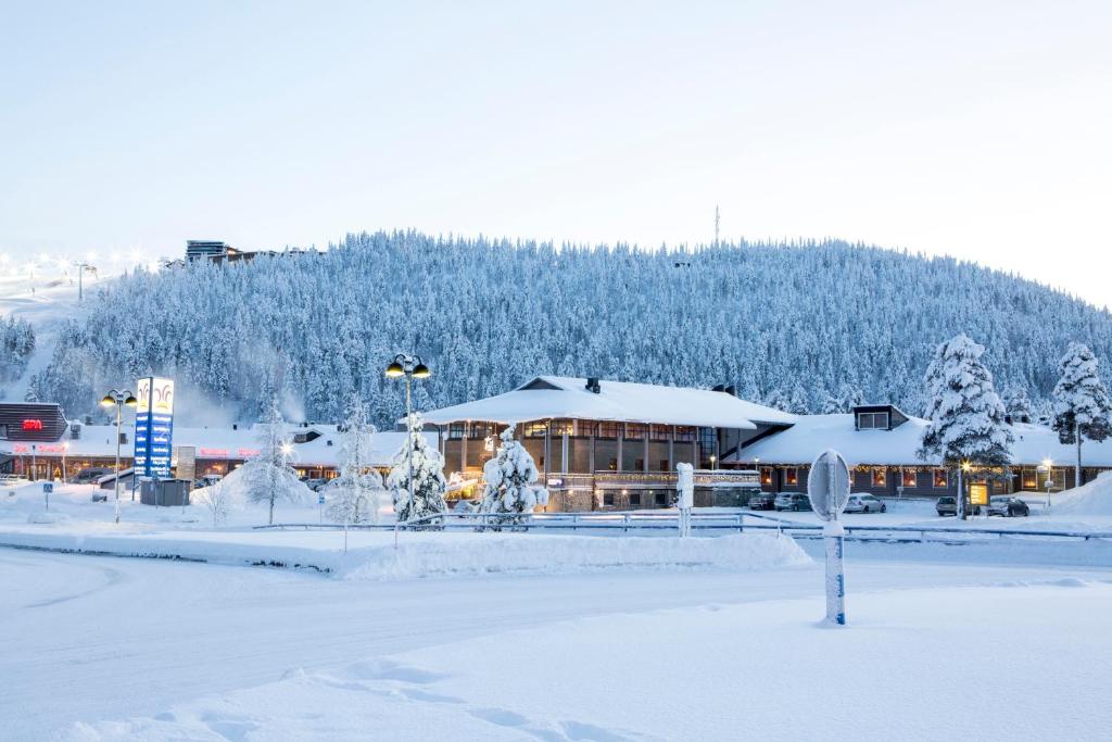 a building covered in snow in front of a mountain at Levi Hotel Spa in Levi