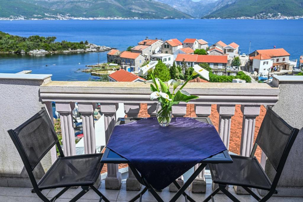 a table with a vase of flowers on a balcony at Apartments Porto Bjelila in Tivat