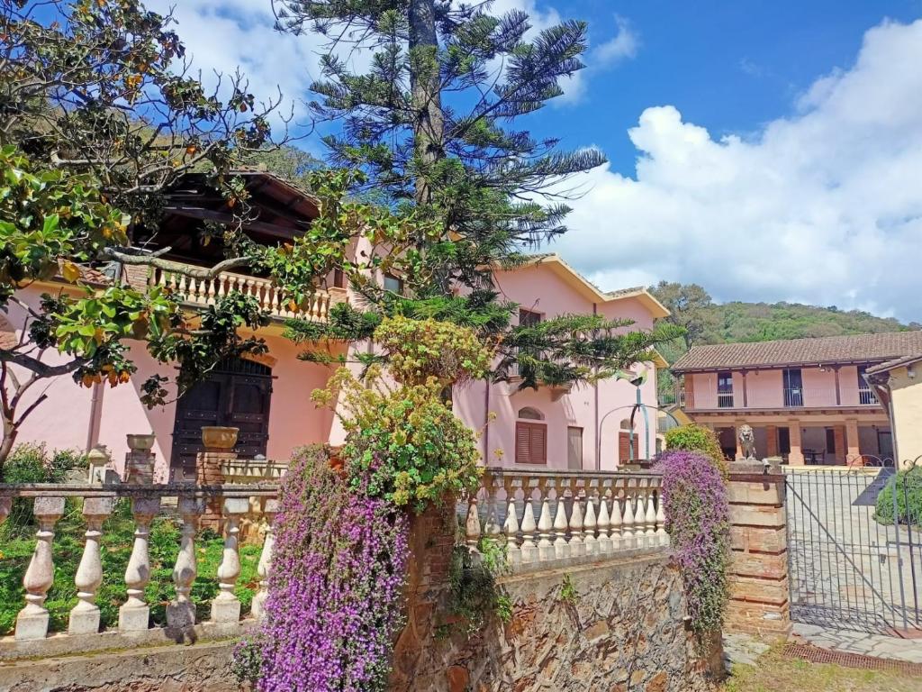 a pink house with a white fence and purple flowers at Il Borgo in Iglesias