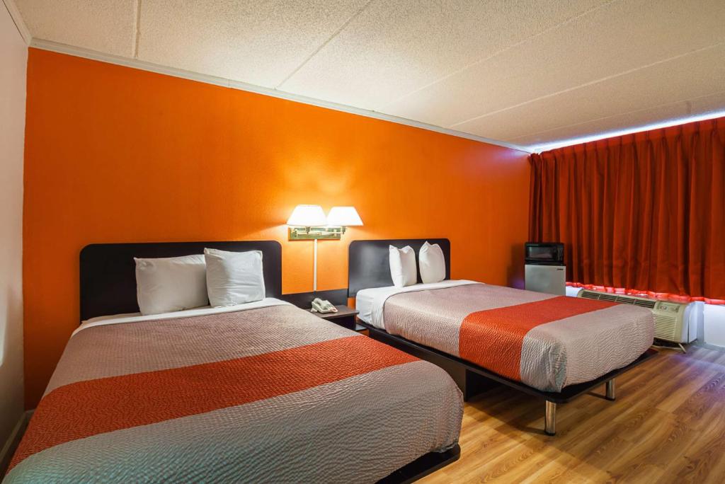 2 camas en una habitación con paredes de color naranja en Motel 6-Tifton, GA, en Tifton