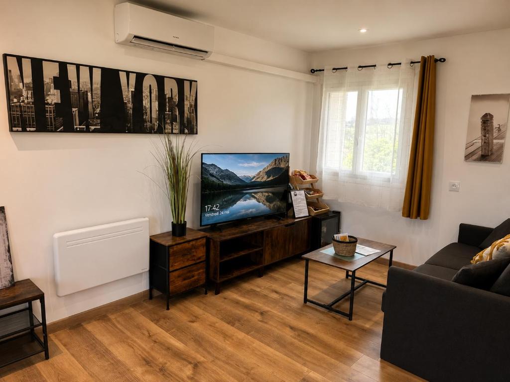 a living room with a flat screen tv and a couch at Entre parenthèses - Grand confort et Parking privé in Le Fousseret