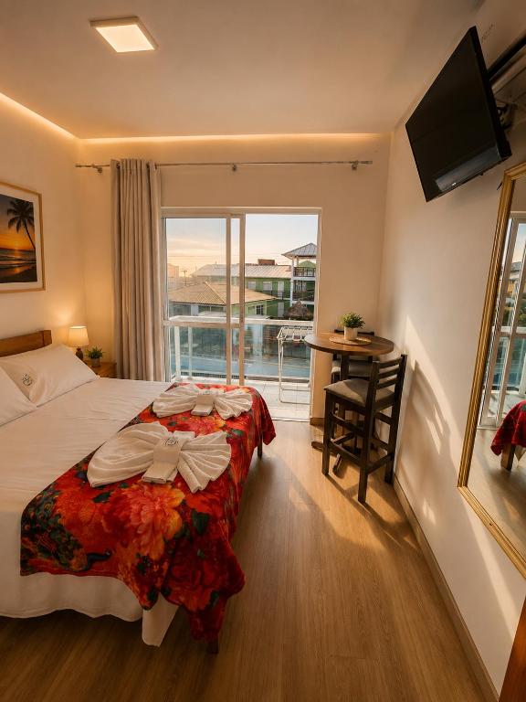 a bedroom with a bed and a window and a desk at GH Barra da Lagoa in Florianópolis
