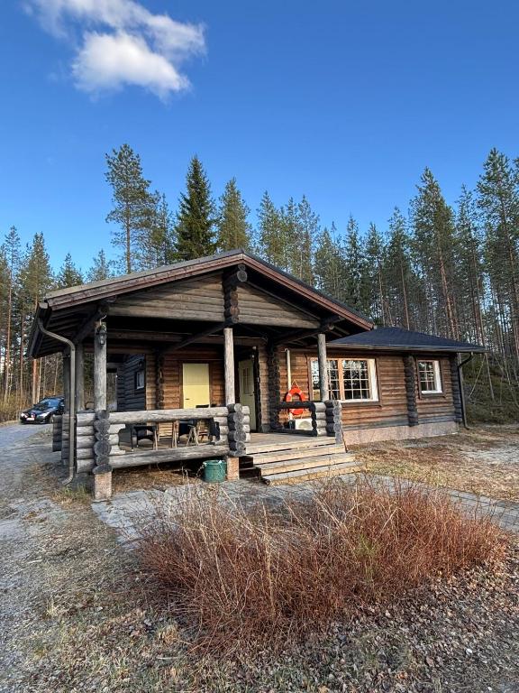a log cabin in the woods with a porch at Kalliorinteen Mökit Lehtipirtti in Töysä