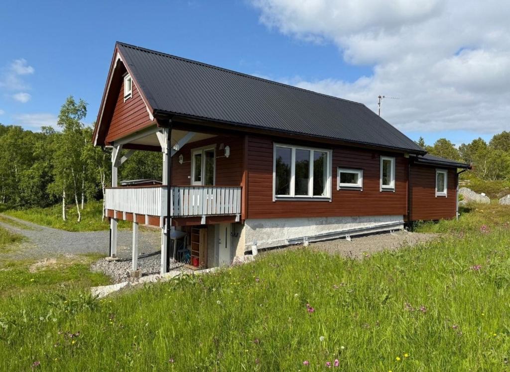 a large wooden house with a balcony on a field at Hytte Lødingen Vestbygd, når Lofoten, med utsikt in Lødingen