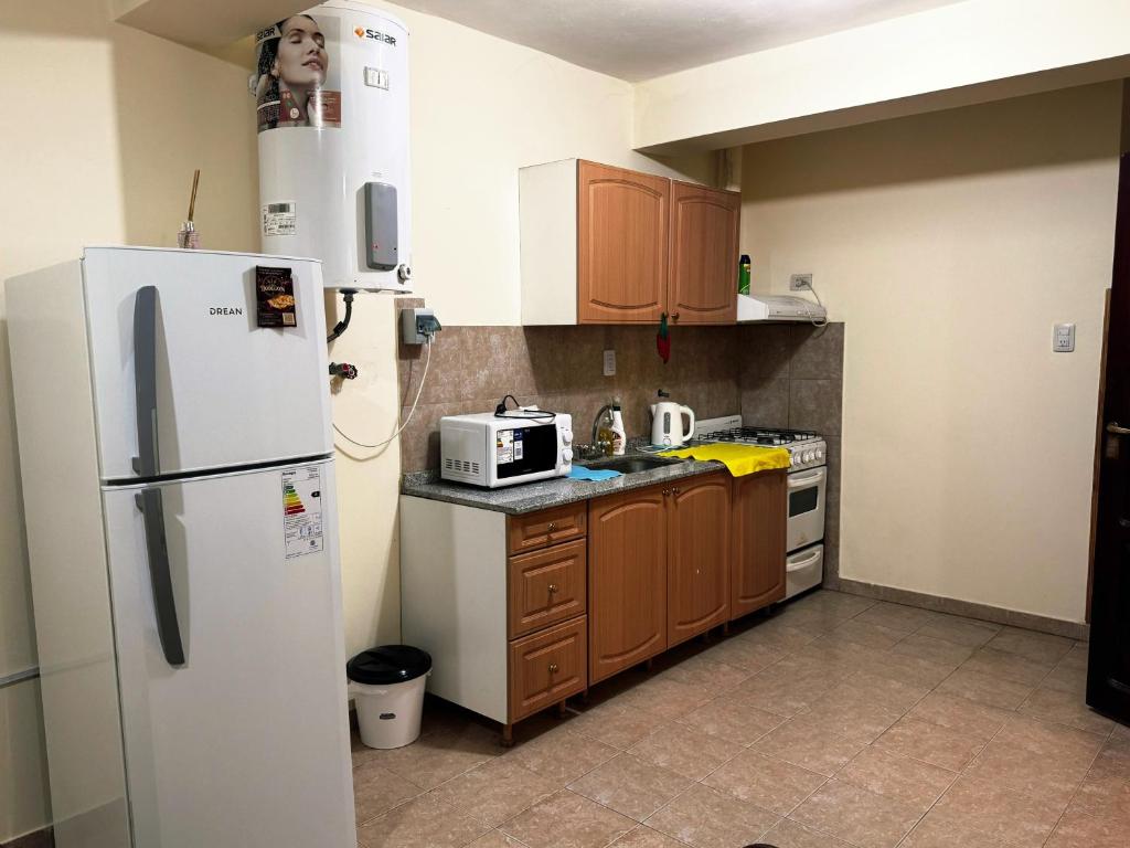a kitchen with a white refrigerator and wooden cabinets at Depto Clarita in Belén
