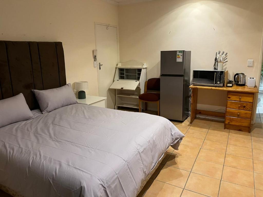 a bedroom with a bed and a desk and a refrigerator at Adorable Pool Side Apartment in Monte Vista