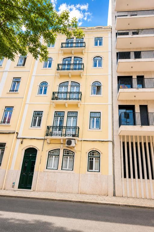 a tall yellow building with windows and a green door at Avenidas Prime Lisbon in Lisbon