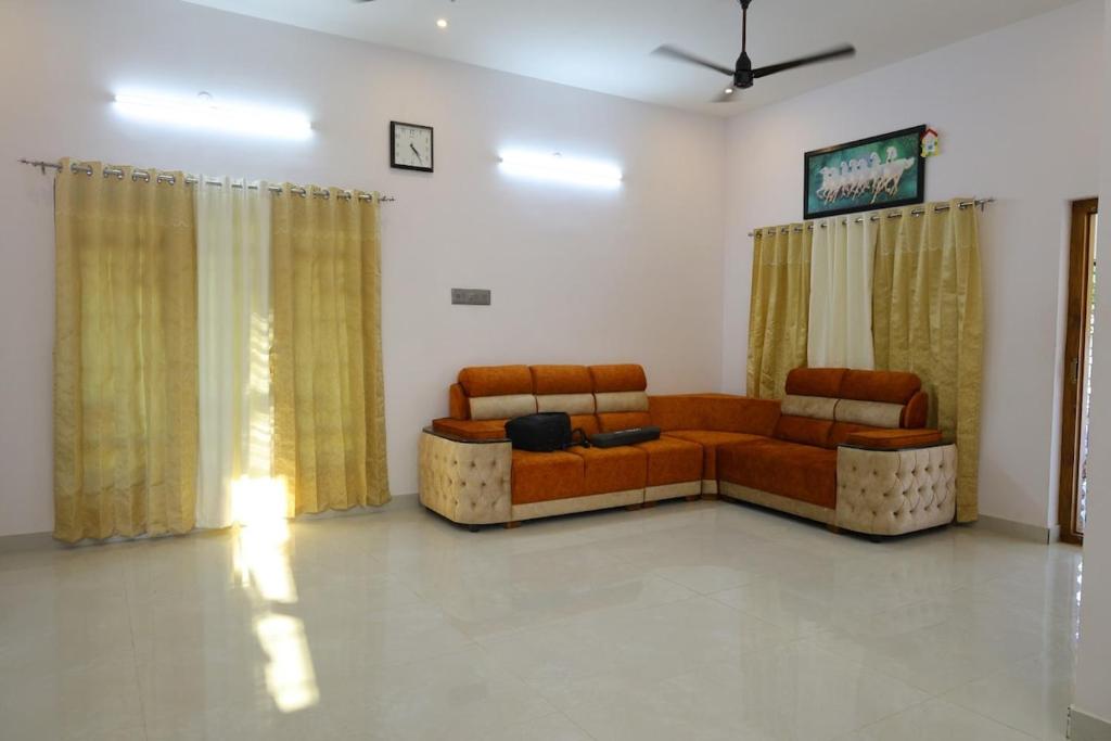 a living room with two couches and curtains at Sarva Tranquil home stay in Kumbakonam