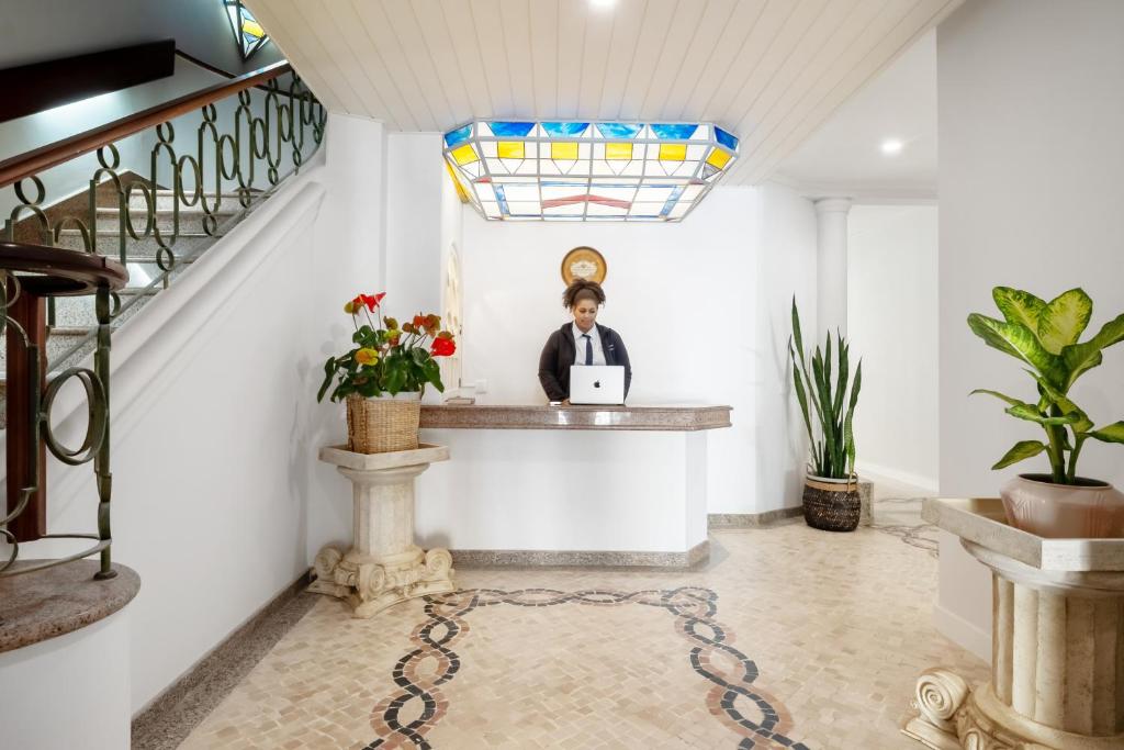 a man sitting at a counter in a room with a laptop at The Royal Guesthouse in Faro