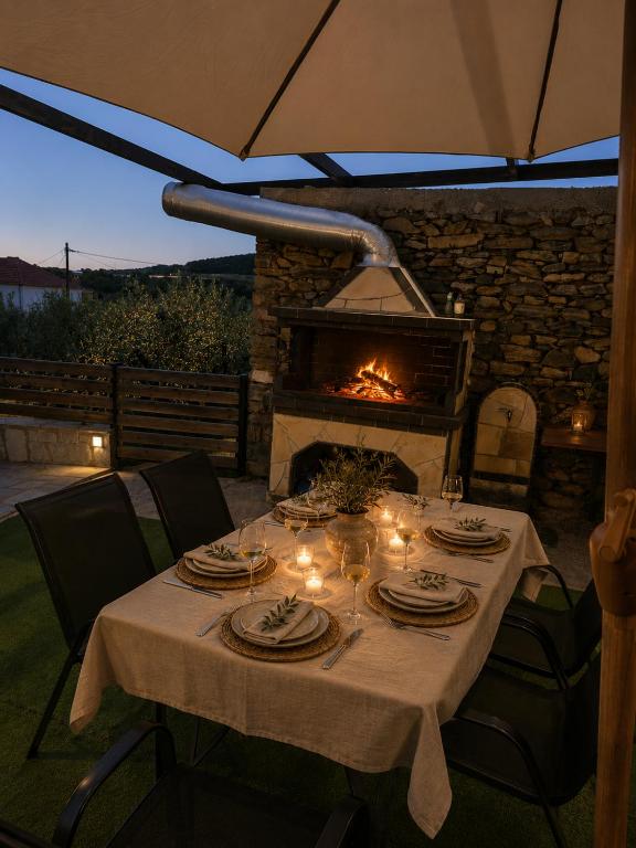 a dinner table with a fireplace in a patio at Olive Tree's House in Elaiokhórion