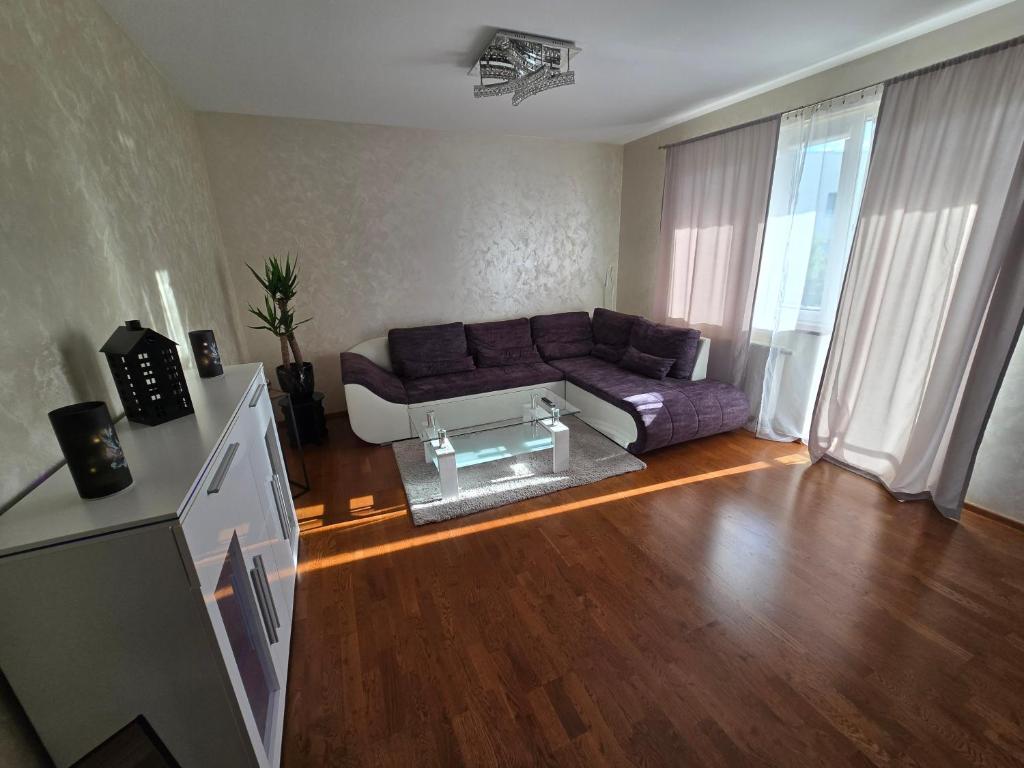 a living room with a purple couch and a glass table at Silent Apartment Płock in Płock