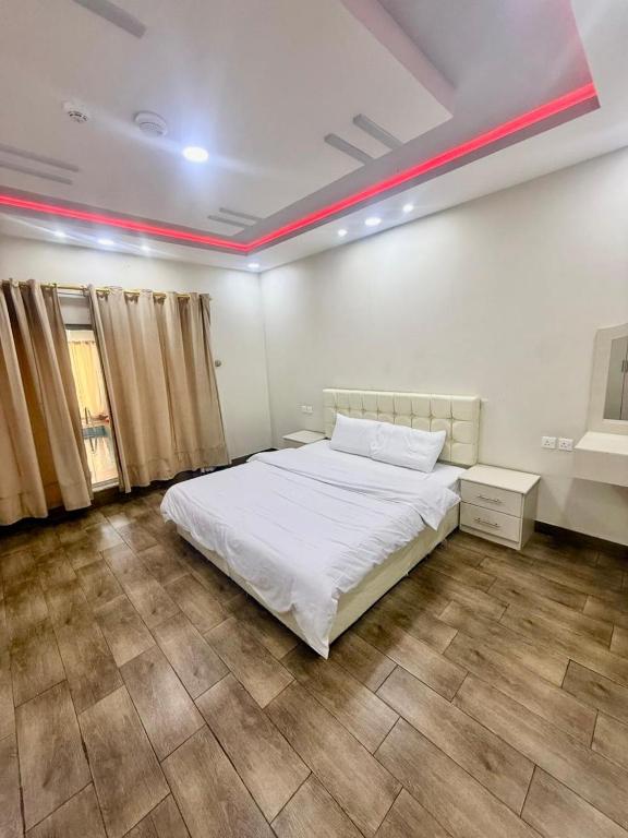 a bedroom with a white bed and a red stripe on the ceiling at Chalets Zara شاليهات زارا in Taif