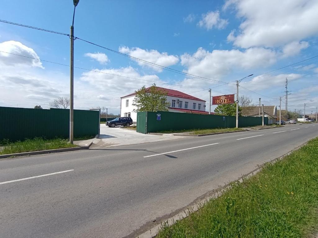 an empty street with a green fence and a building at Отель Гетьман in Broska