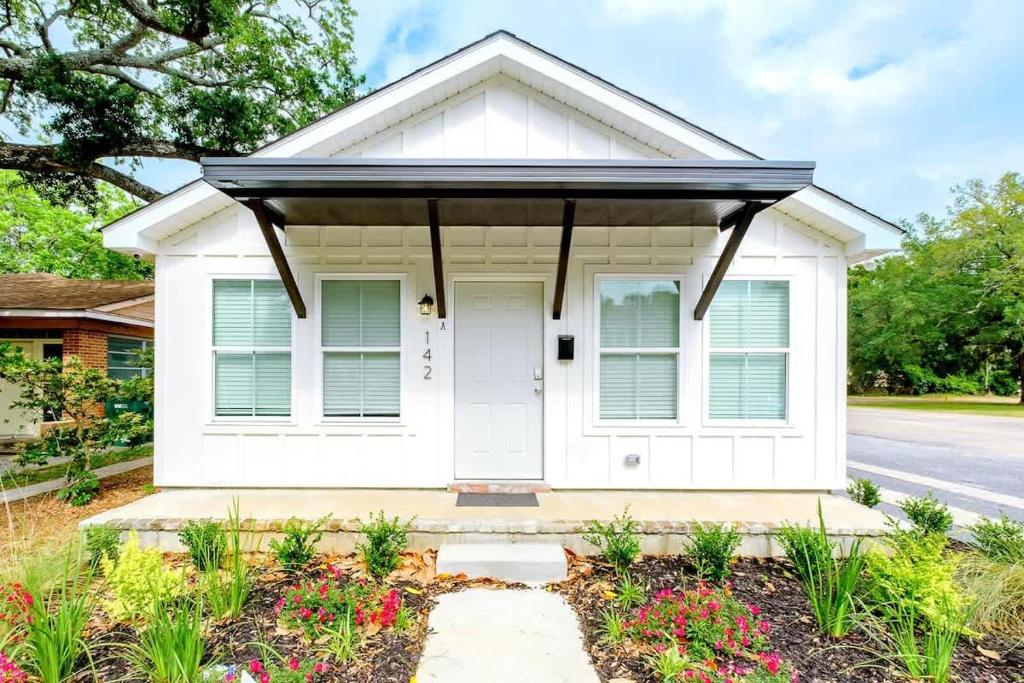 a white house with a porch and flowers at Peaceful Horizons at The Heron's Rest in Biloxi