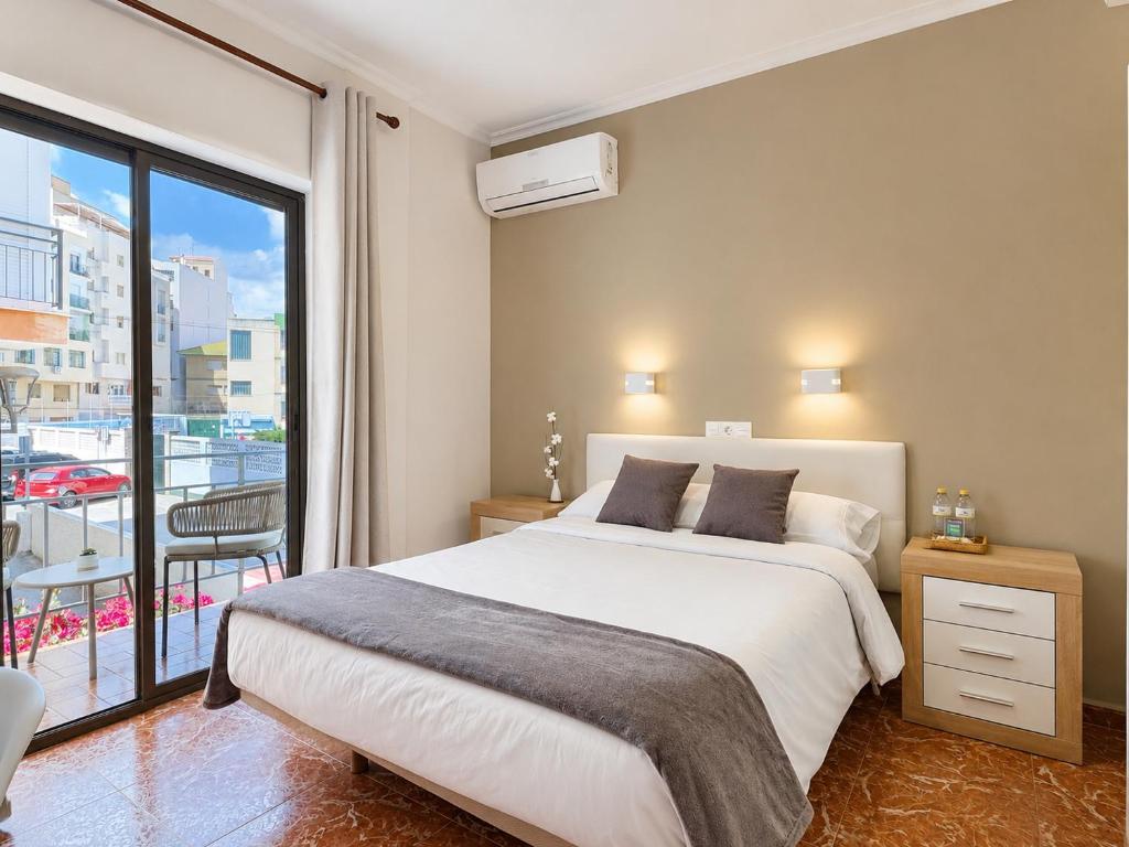 a bedroom with a large bed and a balcony at Pensión Rocamar in Almuñécar