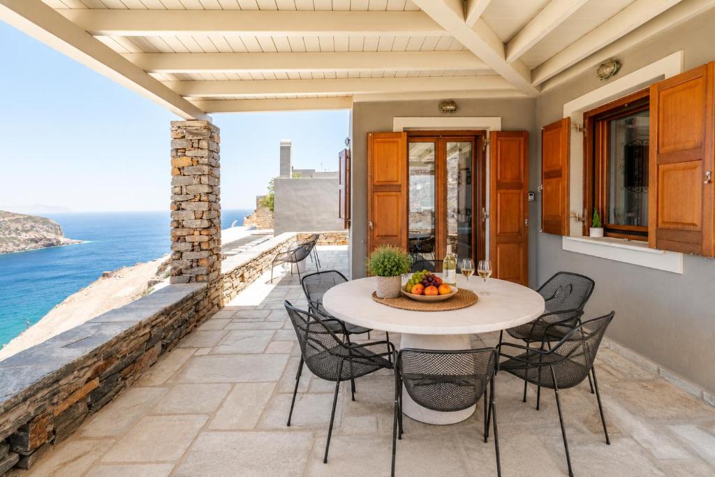 a patio with a table and chairs and the ocean at Marilia VIllage Spathi Kea "Villa Helios" in Spathi 