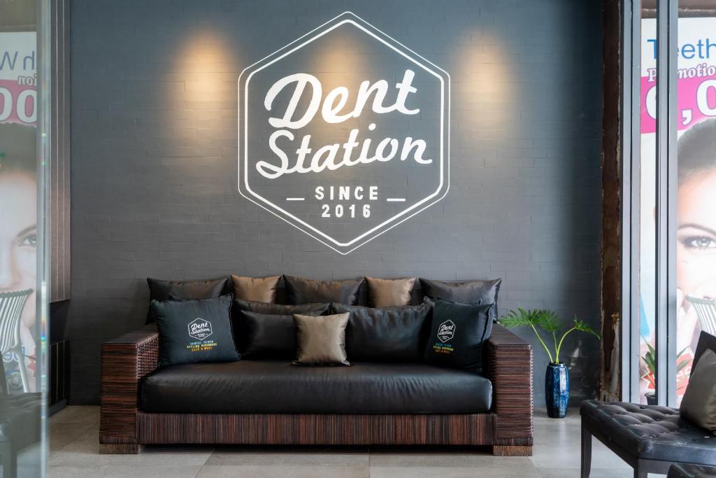 a couch in a room with a sign on the wall at Dent Station Residence in Ban Suan