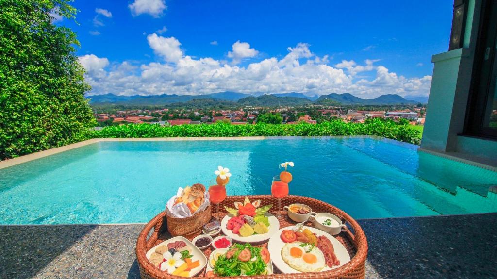 a tray of food on a table next to a swimming pool at Luang Prabang View Hotel in Luang Prabang
