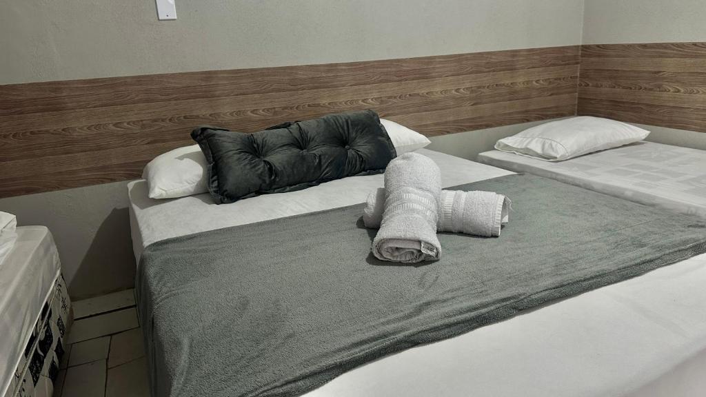 two beds with towels and pillows in a room at Pousada O Leão in Piaçabuçu
