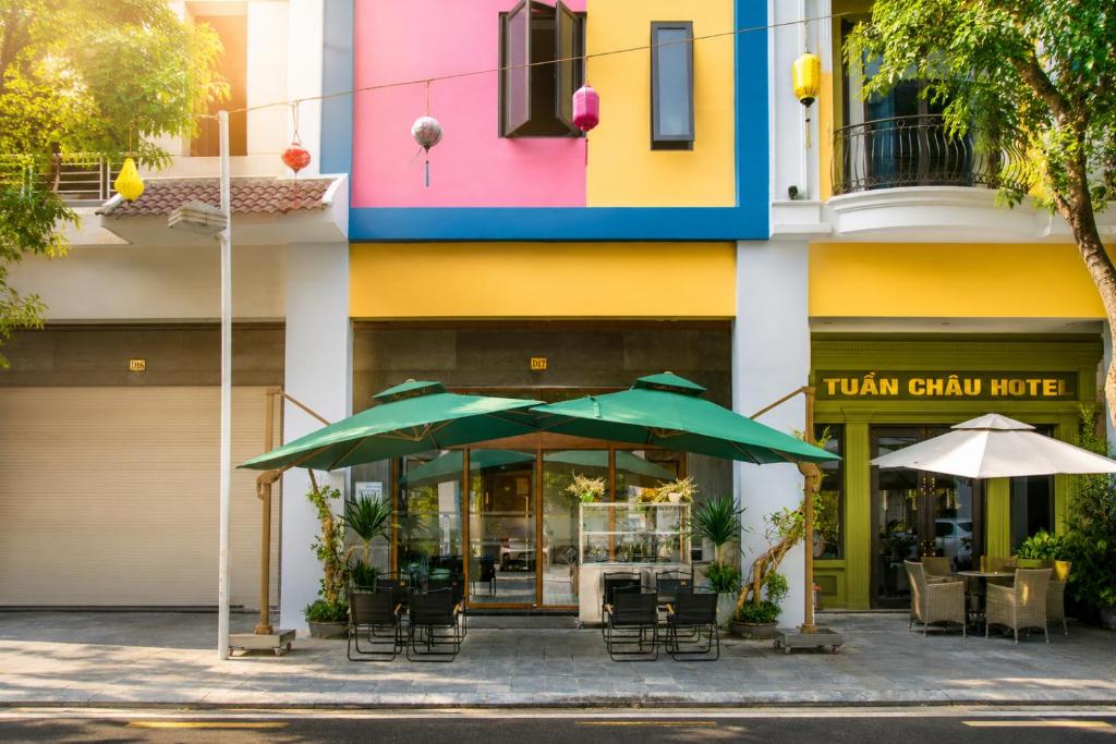 a restaurant with tables and umbrellas in front of a building at Khách Sạn Cát House in Ha Long