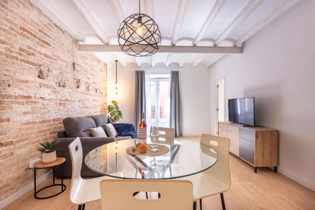 a living room with a brick wall and a glass table at Cavallers Suites - Unik Vacation in Tarragona