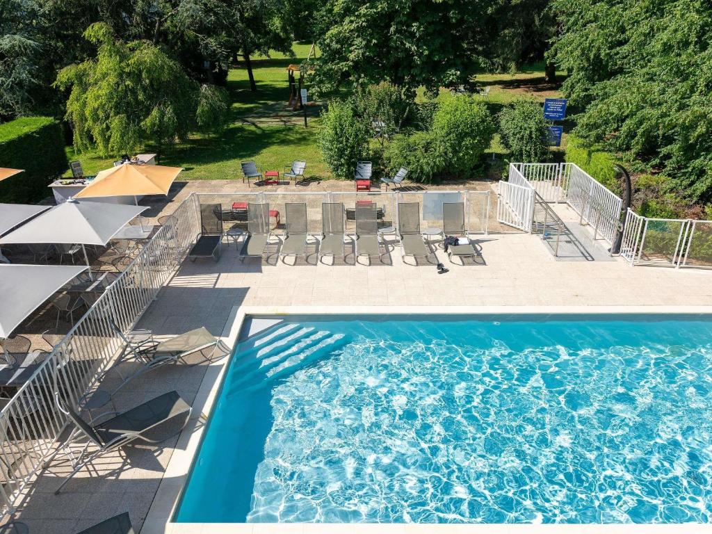 an overhead view of a swimming pool with chairs and tables at Novotel Macon Nord - Porte de Bourgogne in Mâcon