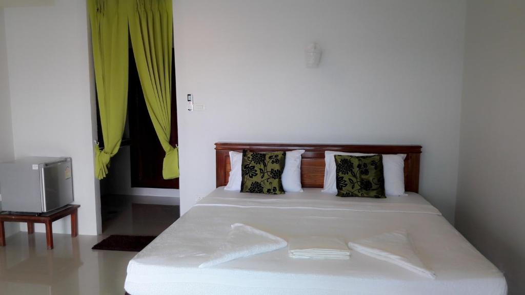 1 cama con sábanas blancas y almohadas en una habitación en Silver Beach Bungalow, en Haad Yao