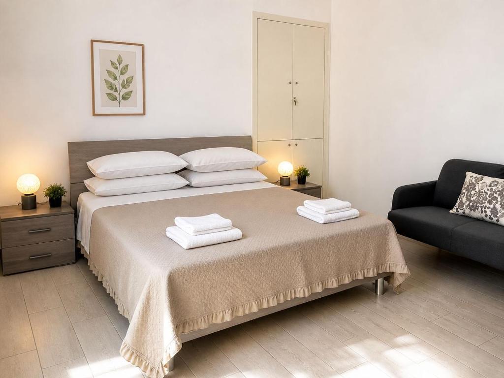 a bedroom with a bed with two pillows and a couch at Life Vesuvio in Torre del Greco