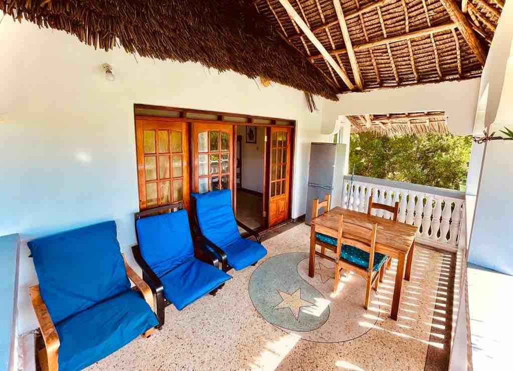 a patio with blue chairs and a wooden table at Kome-Salsa Garden Comfortable big apartment in Jambiani