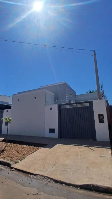 a white building with a gate and a blue sky at Casa Tranquila com Vaga para carro em Três Lagoas in Três Lagoas