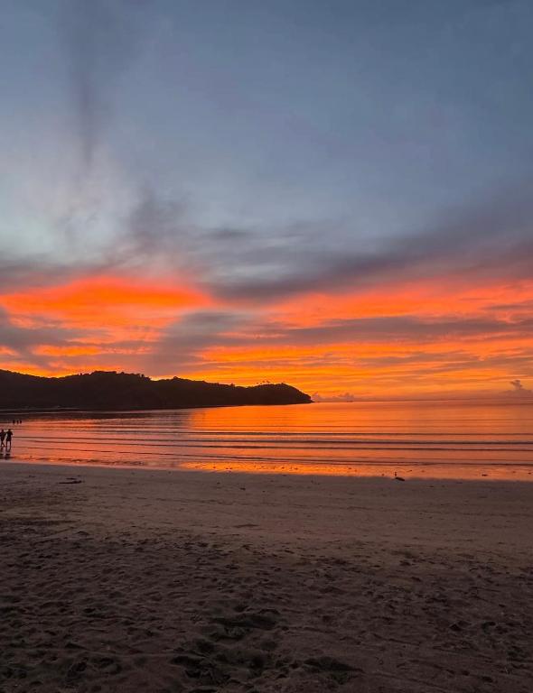 a sunset on a beach with people walking on the sand at Zhaya's Beachfront in El Nido
