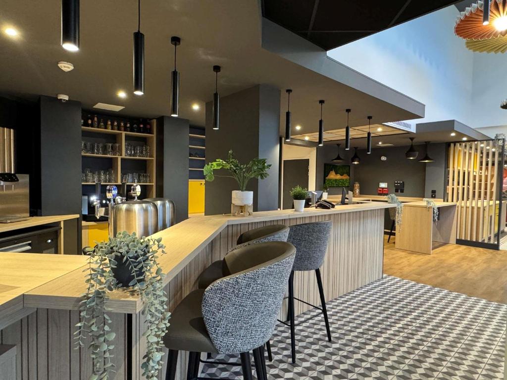 a kitchen with a bar with two chairs and a counter at ibis Clermont Ferrand Montferrand in Clermont-Ferrand