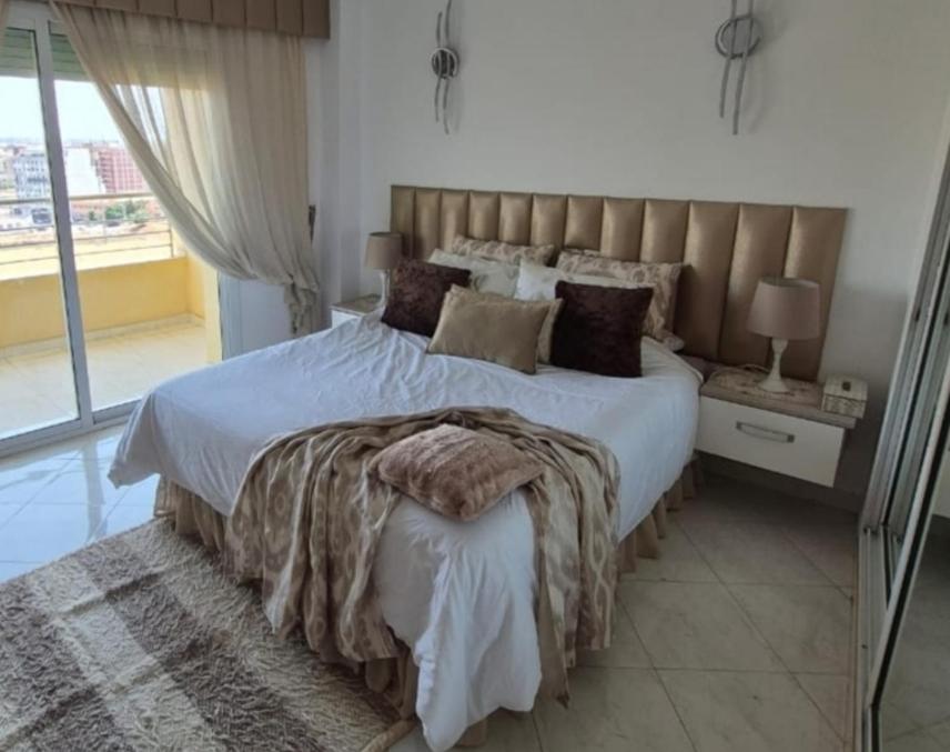 a bedroom with a large bed with a large window at Apartment Konouz Meknes in Meknès
