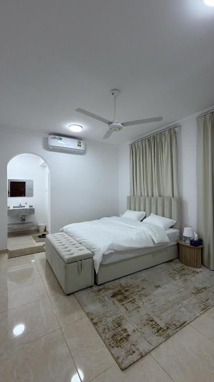 a white bedroom with a large bed and a ceiling at جوهرة الخوض in Al Khawḑ