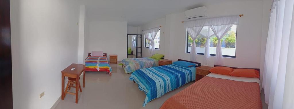 a room with two beds and a table in it at Iguana Marina House in Puerto Villamil