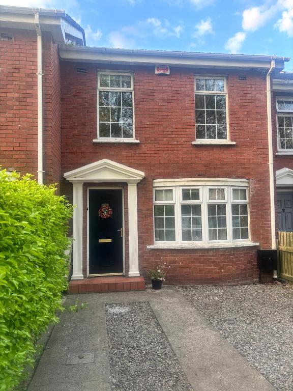a red brick house with a black door at Dublin 12 house in Dublin