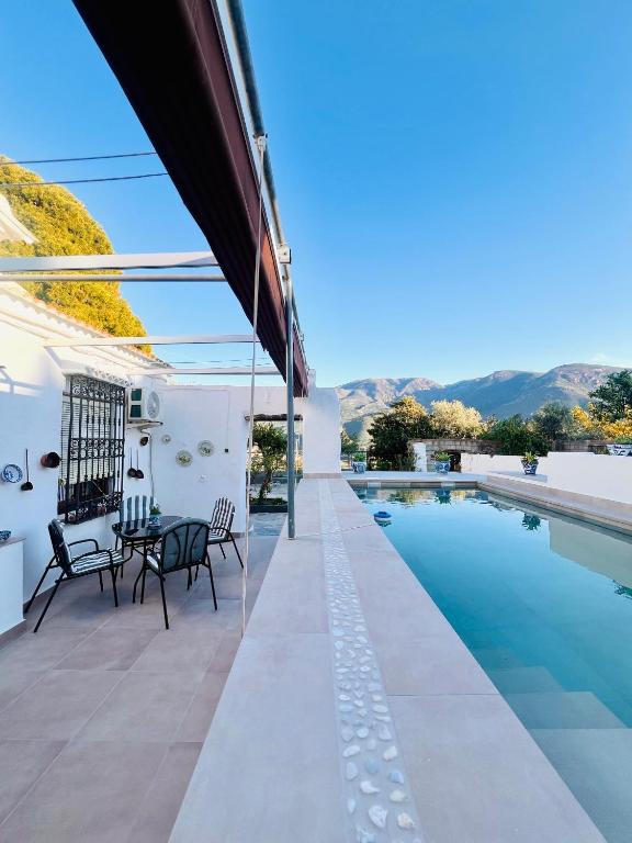 a patio with a table and chairs next to a swimming pool at Huerta La Niña Arenas in Órgiva