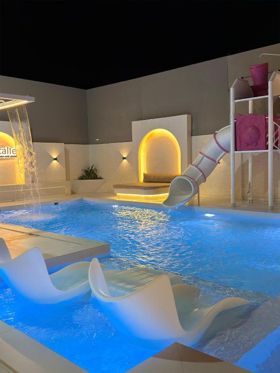 a large pool with a water slide in a room at Natalie Aqua villa heated pool 3BD DeadSea in Al Kafrayn