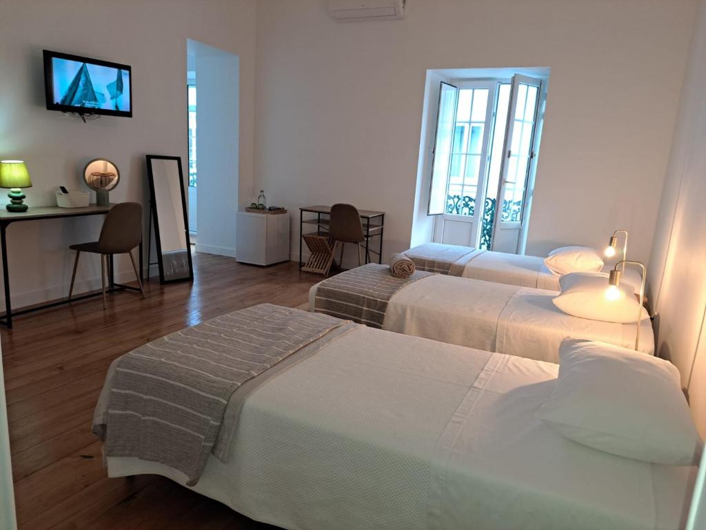 a hotel room with two beds and a television at Jomafreitas in Ponta Delgada