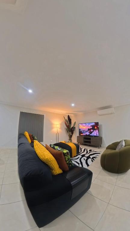a living room with a black couch and a tv at Canaan Oasis in Pimpama