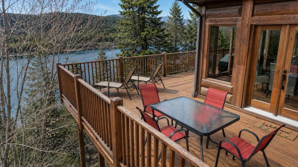 a wooden deck with a table and chairs on it at Belvedere sur le Lac Lodge in Sainte-Adèle