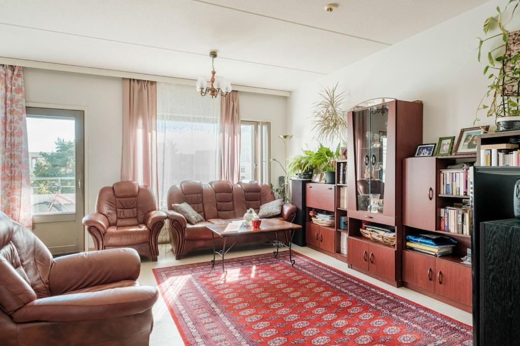 a living room with leather furniture and a red rug at Peace & Harmony in Espoo