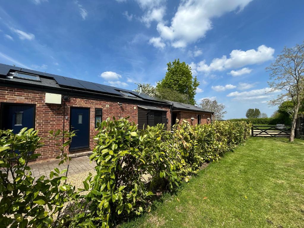 a brick building with a fence and a yard at Cobblers Lodge in Somersham