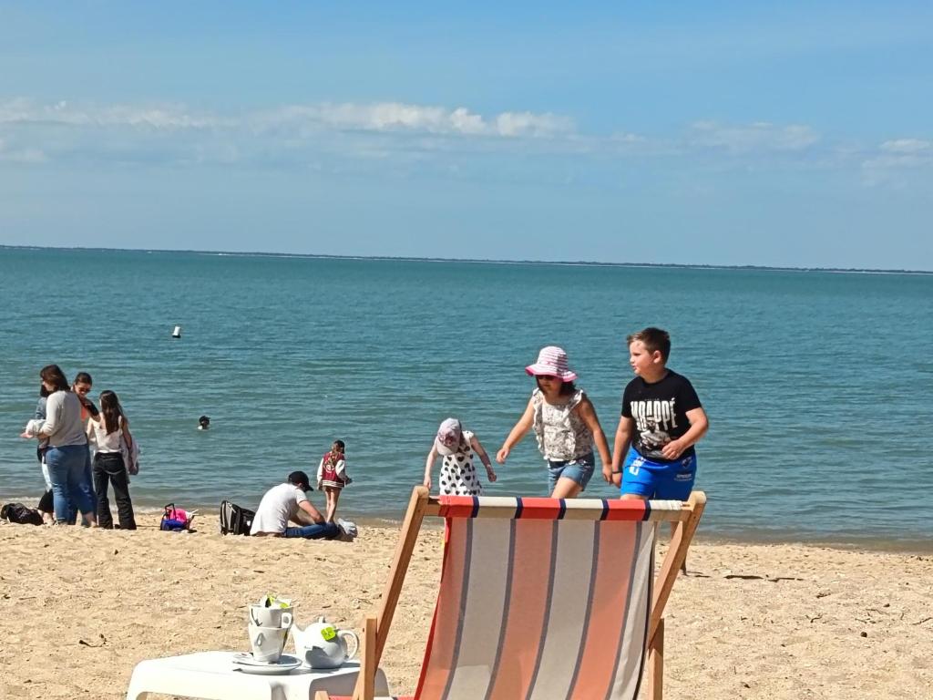 a man and a child sitting on a chair on the beach at Studio cocooning entre Fouras et Rochefort in Saint-Laurent-de-la-Prée