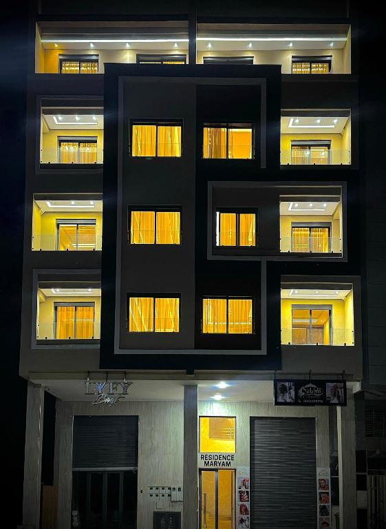a tall building with lit windows and a basketball court at Résidence Maryam in Nador